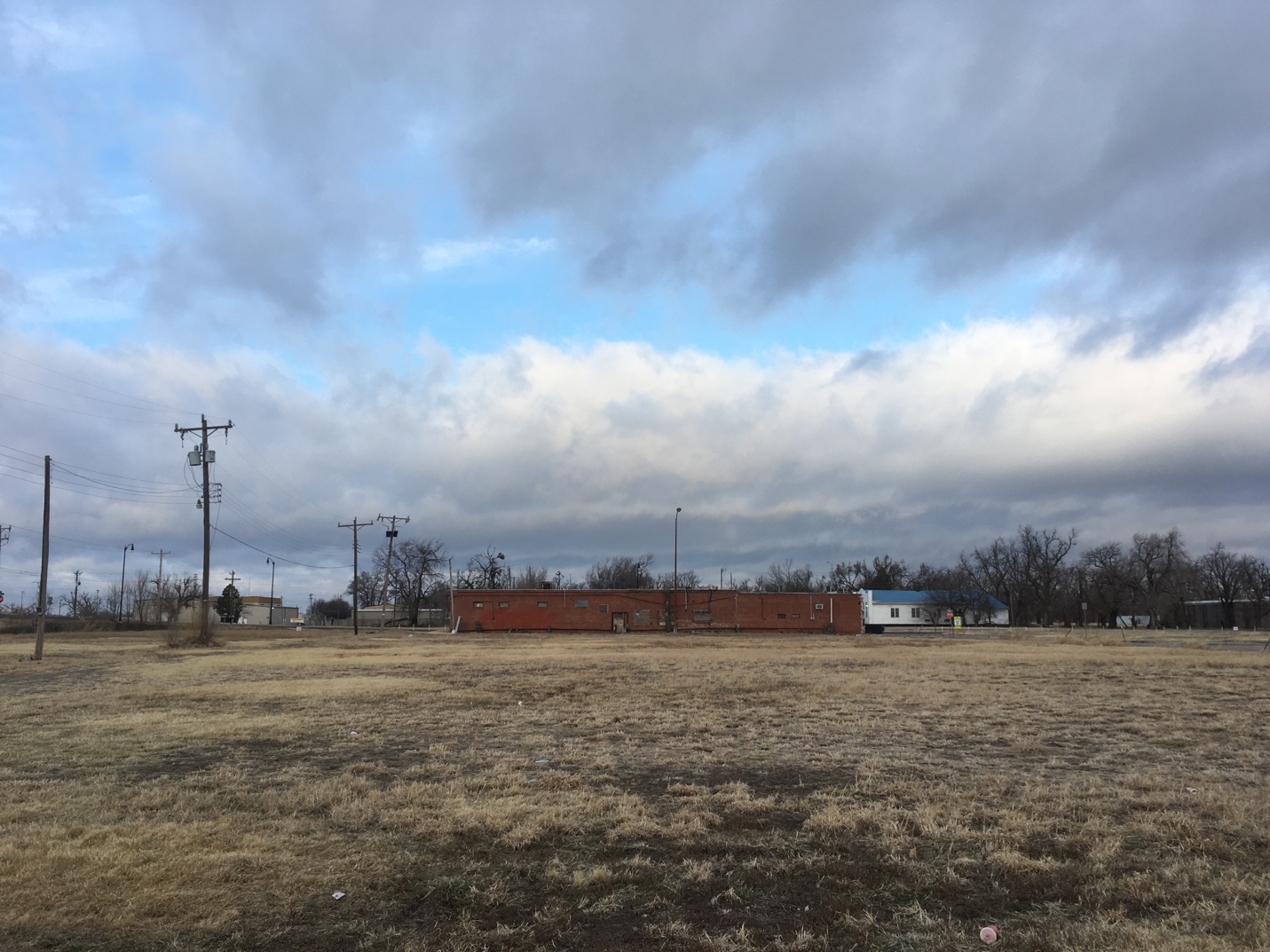 A large field with power lines and buildings in the background
Description automatically generated with low confidence
