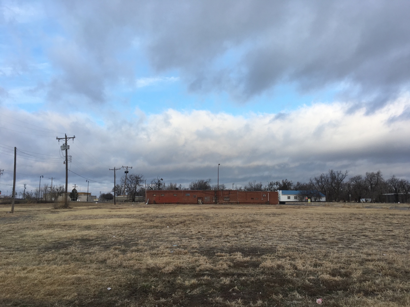 A large field with power lines and buildings in the background

Description automatically generated with low confidence